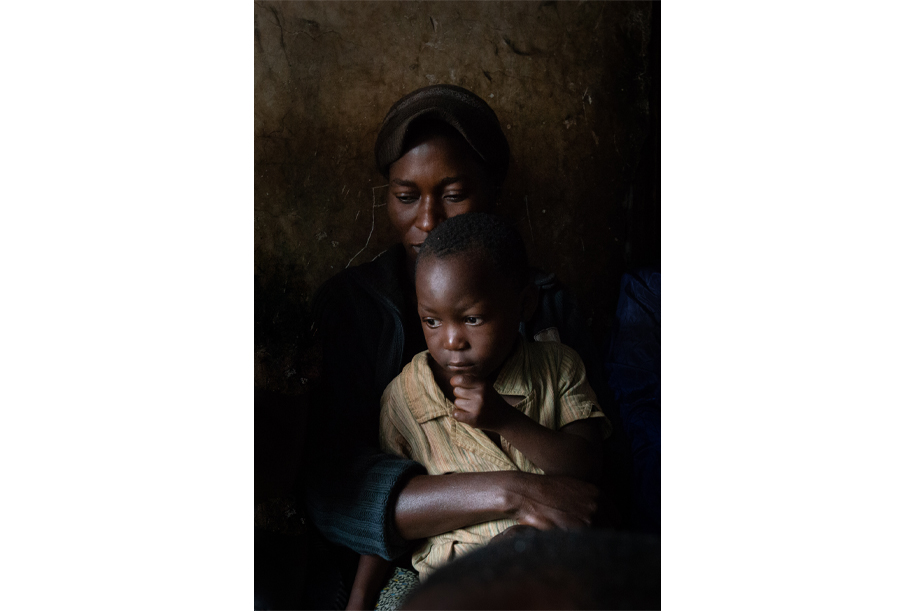 African lady with a child on her lap. Sitting in a dark living room.